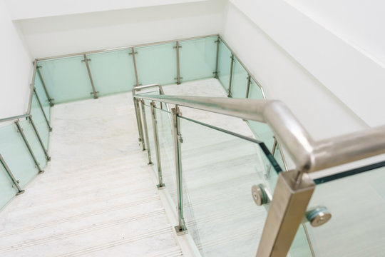 Modern white marble stairs with steel and glass railing in a new modern building.