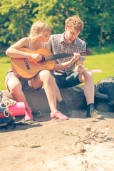 Young couple camping playing guitar outdoor