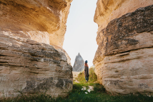 The woman stands between beautiful rocks and admires the landscape in Cappadocia in Turkey