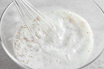 Whipping yogurt with chia seeds in glass bowl on table, closeup