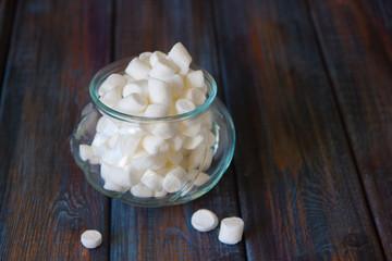 Marshmallows in a glass jar on a wooden table