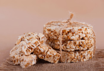 Round cereal crispbread tied with rope, crumbs on surface. Rustic style.