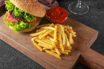 Wooden board with yummy french fries on table