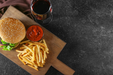 Wooden board with yummy french fries on table
