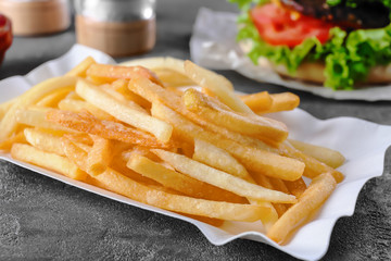 Paper container with yummy french fries on table, closeup