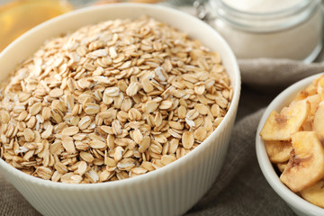 Bowl with oatmeal flakes on fabric, closeup