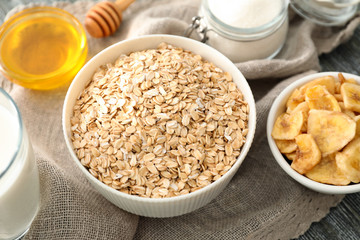 Bowls with oatmeal flakes and banana chips on fabric