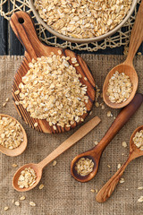 Composition with oatmeal flakes, wooden spoons and board on sackcloth fabric