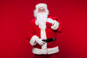 Christmas. santa claus with big bag on shoulder is on red background