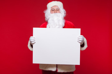 Santa Claus pointing in blank advertisement banner isolated on red background with copy space
