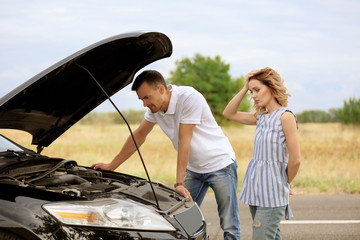 Young couple standing near broken car
