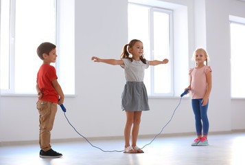 Adorable children skipping rope indoors