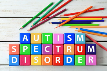 Colorful cubes and pencils on wooden background. Autism awareness concept