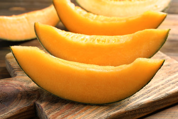 Wooden board with sliced melon on table, closeup
