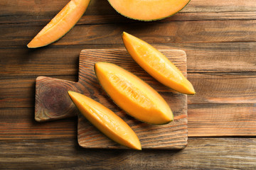 Cutting board with sliced melon on wooden background