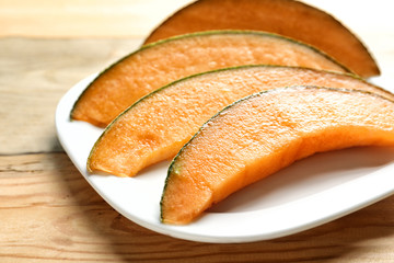 Plate with sliced melon on wooden background, closeup