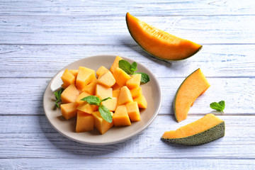 Plate with sliced melon on wooden background