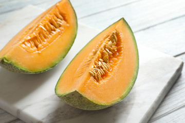Marble board with slices of fresh ripe melon on table, closeup