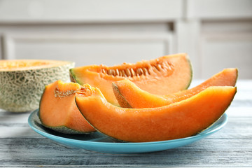 Plate with sliced melon on wooden table, closeup
