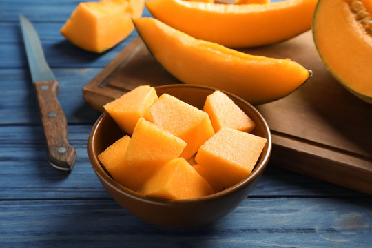 Bowl with sliced melon on wooden background