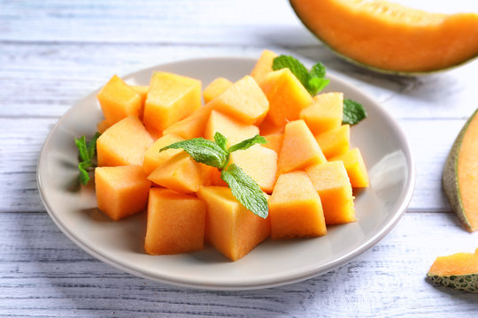 Plate with sliced melon on wooden background, closeup