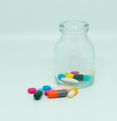 colorful medical pills and tablets with glass bottle on white, close up for medicine.