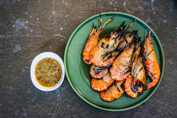 On top grilled prawn, giant freshwater prawn shrimp on green ceramic dish with seafood sauce dipping
