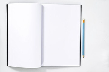 Blank white open notebook or magazine page on white wooden table with pencil on notebook for mockup designs