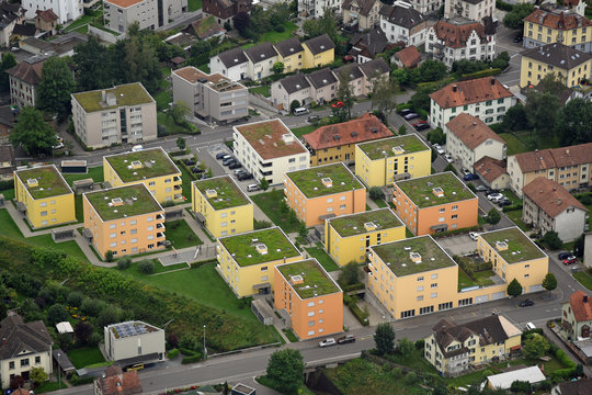 Luftaufnahme von in Gelbtönen angemalten vierstöckigen Mehrfamilienhäusern mit begrünten Dächern in der Schweiz