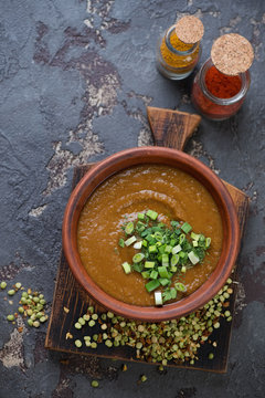 Soup with dried green split peas and curry in south asian style, top view on a brown stone background
