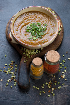 Bowl of pea cream-soup with curry on a rustic wooden serving board, selective focus, studio shot