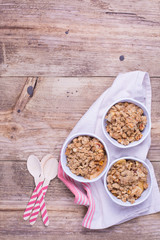 Apple crumble served in individual white ramekins placed on top of a cotton dishtowel. Rustic wood background. Copy space. 