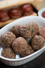 Closeup of a white bowl with baked beef meatballs, selective focus, shallow depth of field