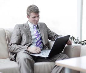 Young businessman sitting at office lobby working with laptop