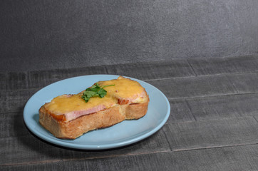 Sandwich with meat, cheese and greens on a blue plate