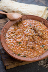 Clay plate of traditional georgian soup kharcho served with lavash, selective focus, vertical shot