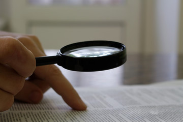 the person reads the document through a magnifying glass