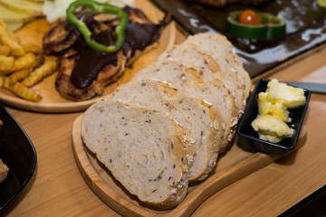 A slice of bread with butter on wooden plate