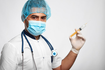 Confident male medical worker wearing hat and mask posing with a syringe in his hand looking to the camera confidently copyspace medicine healthcare protection people vitality prevention surgery.