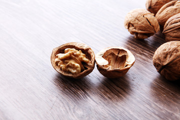 Walnut kernels and whole walnuts on brown wooden table.