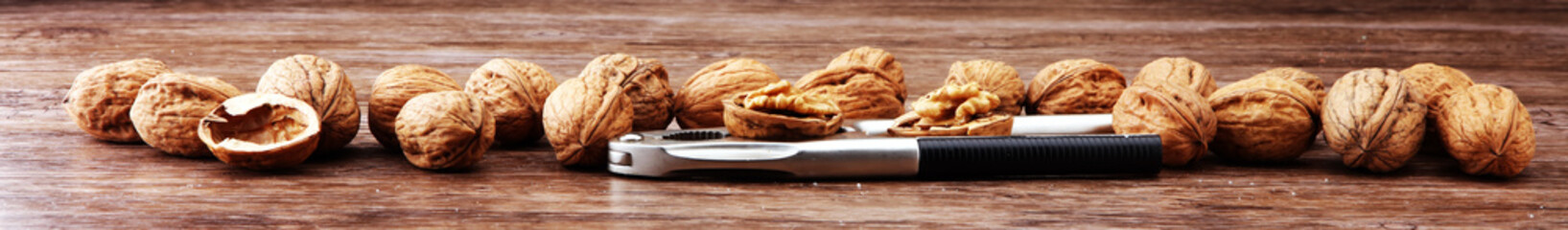 Walnut kernels and whole walnuts on brown wooden table.