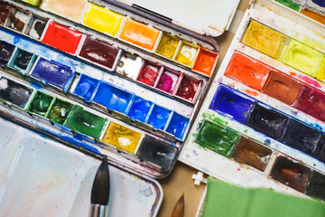 Top view from above on a palette of watercolors prepared by the artist for drawing. Brushes and...