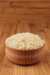 Fototapeta na wymiar White rice basmati in wooden bowl on brown bamboo board, closeup.