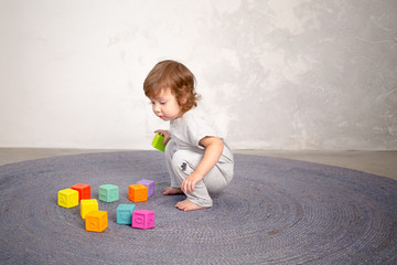 Naklejka premium Little happy girl playing with toy on floor. Kindergarten.