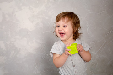Fototapeta premium Little girl playing with toy on gray wall background. Kindergarten.
