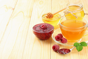 healthy background. raspberry with raspberry jam, honey and tea on light wooden background. top view with copy space