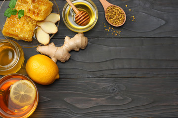 healthy background. honey, honeycomb, lemon, tea, ginger on dark wooden table. Top view with copy space