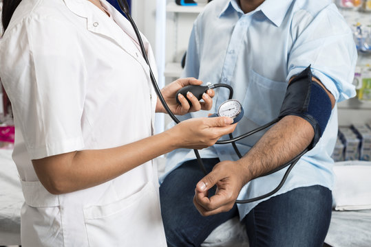 Doctor Holding Dial While Measuring Man's Blood Pressure