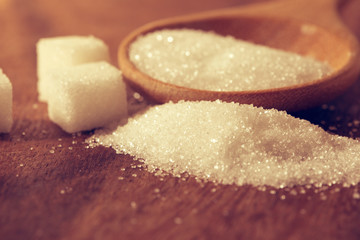 Close up  sugar cubes and cane in wooden spoon on the table ,retro color tone