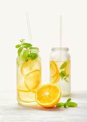 homemade lemonade with fresh citrus and twig mint with drinking straw on wood background